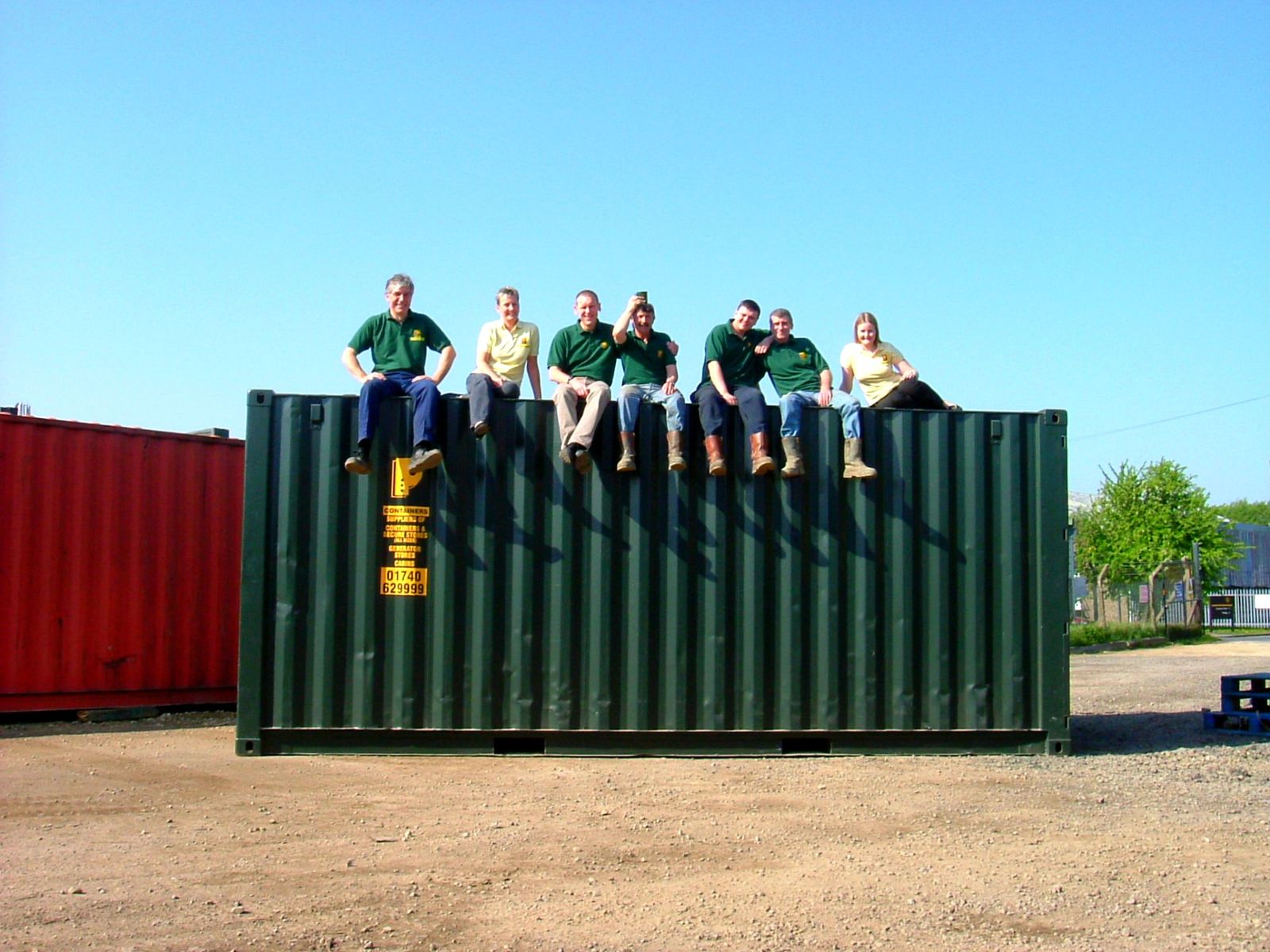 The Parsons Containers team sitting on top of a green shipping container