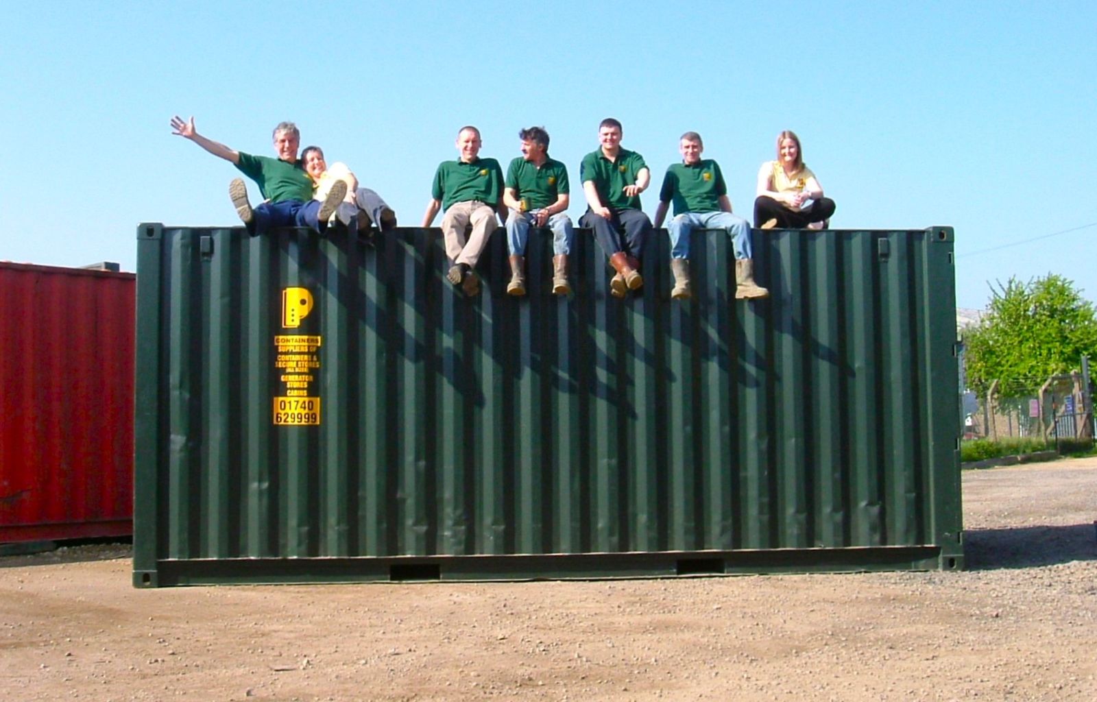 The ContainersNow team sitting on top of a green shipping container at the Darlington depot